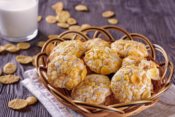 Tasty and beautiful cornflakes cookies in a basket and a glass of milk on a wooden table