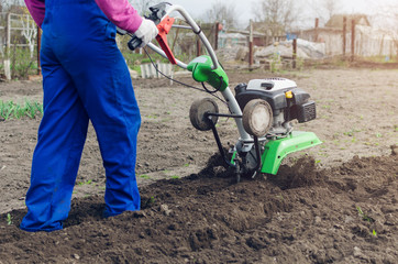 Young girl working in a spring garden with a cultivator