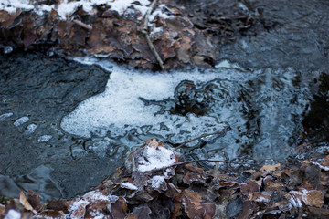 water flowing over rocks with ice in winter
