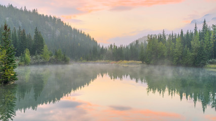 Morning mist on the Cascade Pond with beautiful water reflection at Banff National park