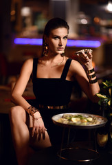 Beautiful sexy fashion brunette woman in expensive interior restaurant eat oysters 