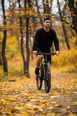 Obraz premium Young fit man during a bike ride on a sunny day in autumn park