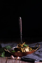 Spaghetti with spinach and dried tomatoes. Fork pounded in spaghetti on a plate.