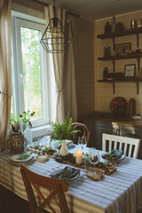 rustic country kitchen interior with festive table setting for summer dinner in natural green and...