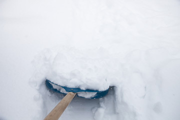 Cleaning snow with shovel in winter day