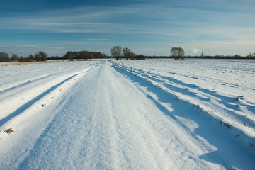 Road and fields covered with snow, horizon and blue sky
