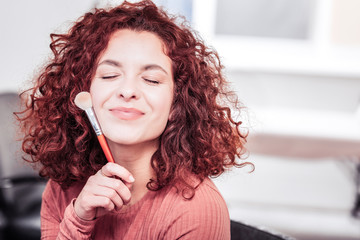 Joyful nice woman holding a makeup brush