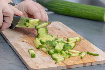 Woman chopping cucumber on wooden board