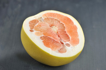 Half pink pomelo on a dark background. Close-up. 
