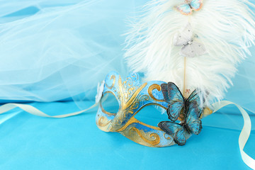 Photo of elegant and delicate gold and blue venetian mask over turquoise silk and chiffon...