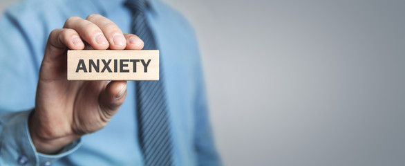 Man showing Anxiety word on wooden block.