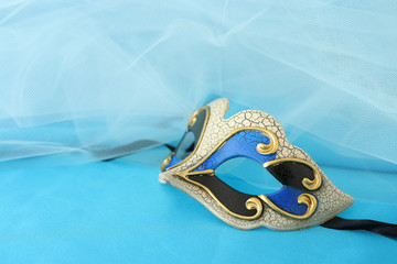 Photo of elegant and delicate gold and blue venetian mask over turquoise silk and chiffon...