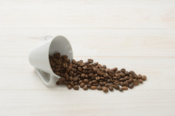 Granos de café en una taza en la mesa de madera blanca