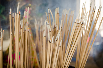 Incense sticks and smoke are burning in incense pot
