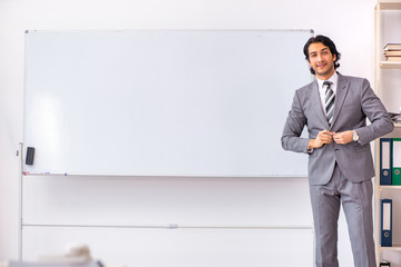 Young handsome businessman standing in front of whiteboard 