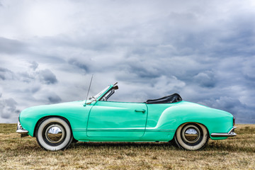 Side view of a beautiful green european covertible. The roof Of this beautiful ghia karmann is open