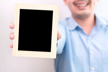 Young businessman showing a wooden blackboard for writing text with advertising in the office.