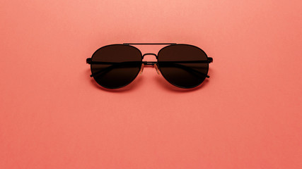 Black sunglasses on coral background. Top view. Flat lay. Copy space. New minimal creative concept....