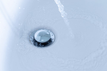Water jet beside silver sink beside white drain in bathroom