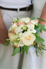 the bride is holding a pink and beige wedding bouquet of fresh flowers and eucalyptus