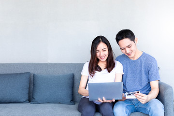 Lovely young pregnant couple sitting on couch with laptop computer.