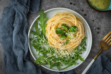 spaghetti with arugula and cheese, top view, close-up