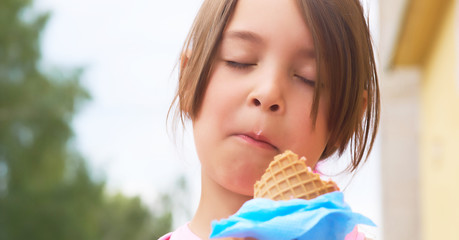 Pretty little girl eating licking big ice cream in waffles cone happy laughing on nature background