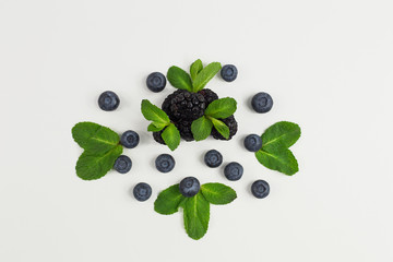 Fresh berries on white background. Place for text. The view from the top. Blueberries and blackberries and mint Leaves