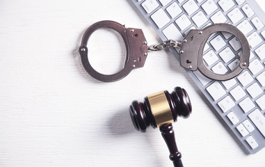 Handcuffs and Judge Gavel with computer keyboard. Concept of  Cyber crime and Online fraud