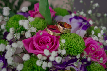 Wedding bouquet with wedding rings. Gold wedding rings lie near the bouquet for the bride. Wedding accessories