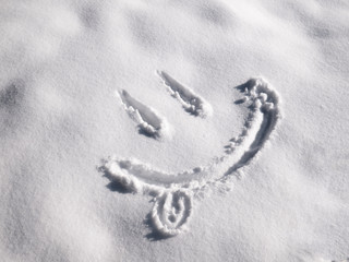 Smile emoji painted on the snow, close-up, top view
