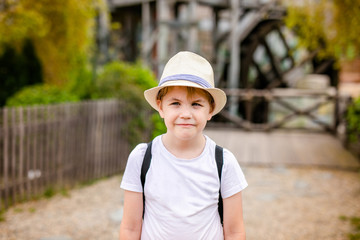 Blonde boy with strabismus in the straw hat in the entertainment park