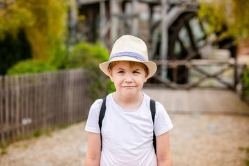 Blonde boy with strabismus in the straw hat in the entertainment park