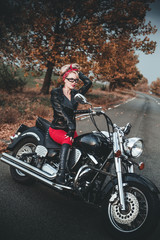 Plakat Beautiful biker woman posing outdoor with motorcycle. Pin-up style. 