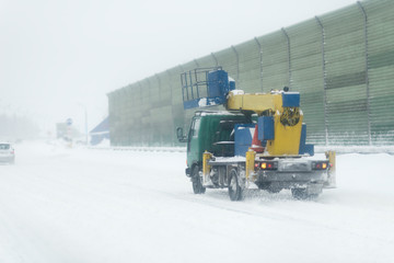 city traffic car road winter snow. Truck with a lifted cabin. Road with noise barrier