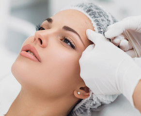 beautician installs the mesothreads in the face of the woman. Anti-aging cosmetic procedures