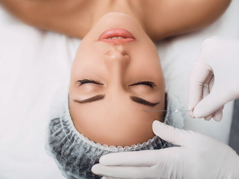 beautician installs the mesothreads in the face of the woman. Anti-aging cosmetic procedures