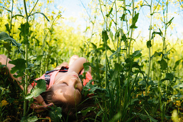 Fototapeta premium girl model laying in field of yellow flowers and tall green grass