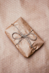Parcel package wrapped with brown craft paper tied rope. Boxing process. Vertical.
