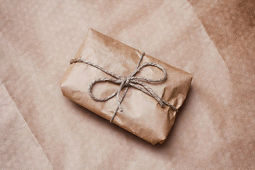 Parcel package wrapped with brown craft paper tied rope. Boxing process. 