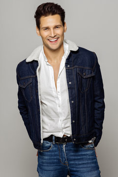 Young handsome man wearing jeans outfit and smiling isolated over gray background