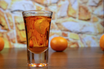 Tangerine liqueur in a glass close up and tangerines