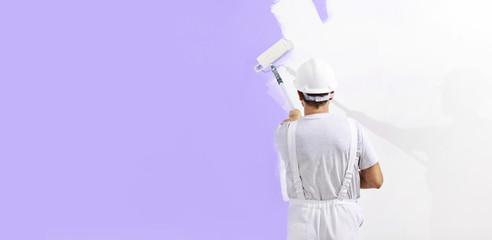 painter man at work with a paint roller, wall painting concept, web banner and copy space template