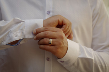 The man fastens the cuffs of the shirt. Morning of the groom