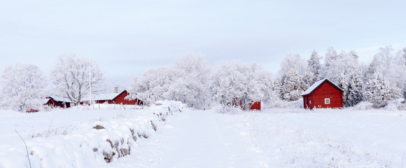 Farm barn and house in a cold winter landscape with snow and frost