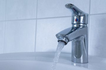 Close up of silver tap with splashing water jet in the bathroom