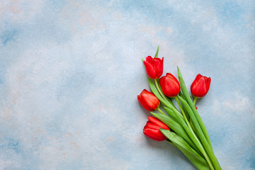 Bouquet of red tulips. Concept for Valentine's Day, womens day and other romantic events. Top view, close-up, flat lay on blue background