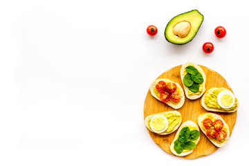 Healthy snacks. Set of toasts with vegetables like avocado, guacamole, rocket, cherry tomatoes on white background top view copy space
