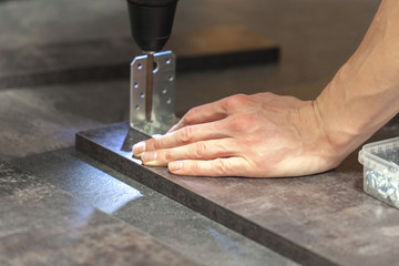 master assembles wood panels with a screwdriver