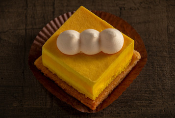 Beautiful yellow cake on a brown wooden table, top view